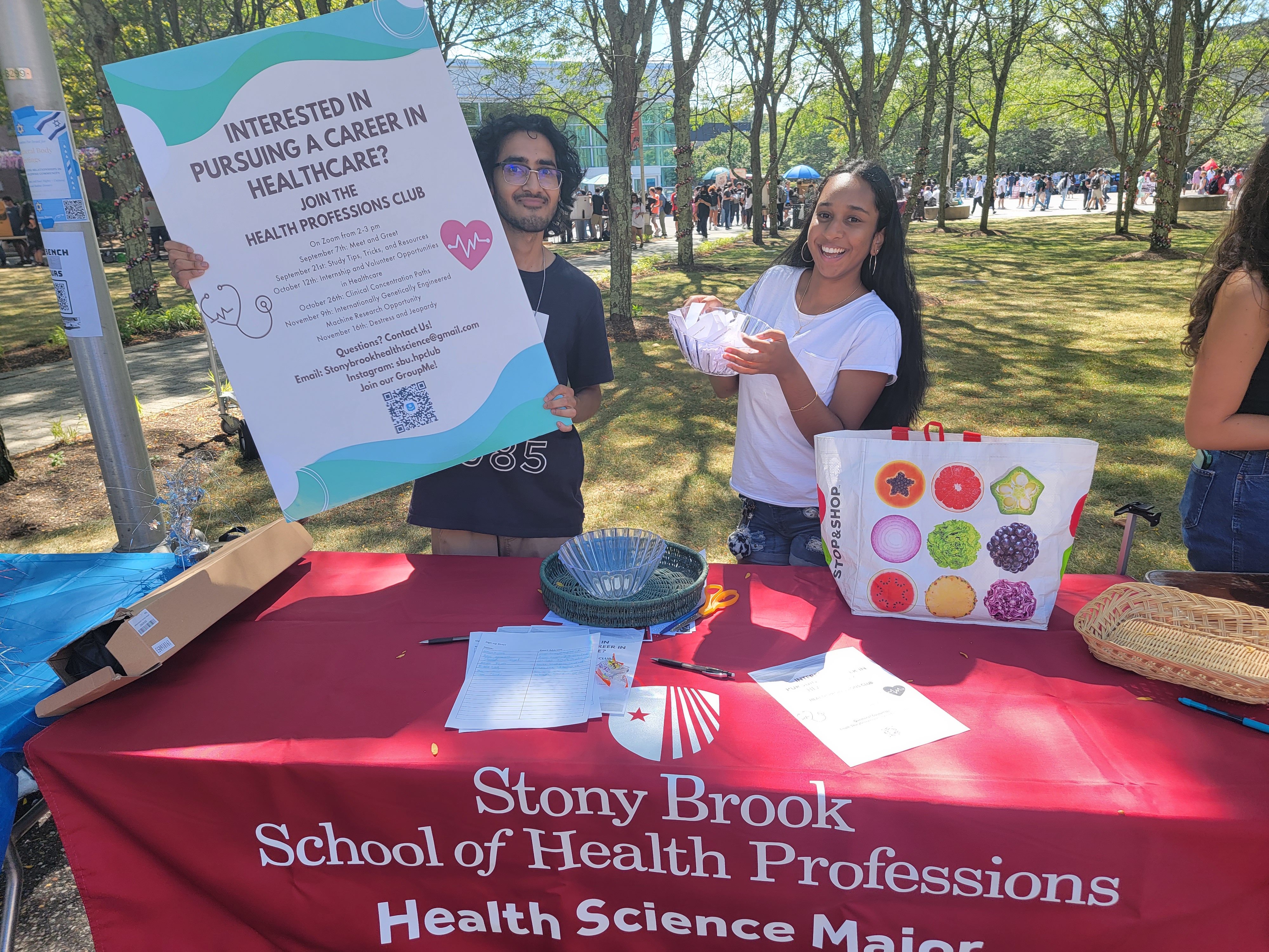 Students outside at a table.  One student holding a sign that says Interested in pursuing a career in health care