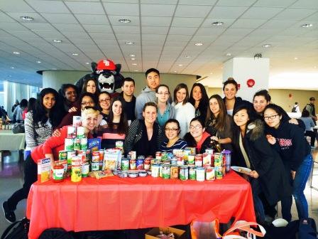 At the OT food drive, OT students gather around a table of donated food along with the Wolfie mascot